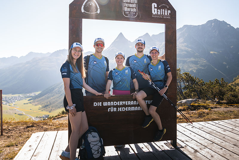 Fünf Athleten auf Bergspitze mit Walking-Stock