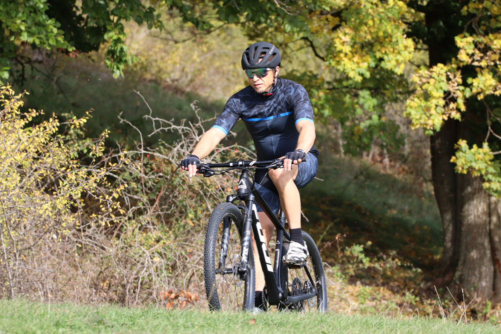 Radfahrer im Herbst mit Mountainbike und Helm. Trägt DOWE Sportswear SuperForm Race Kurzarm-Trikot "Blue Camo"